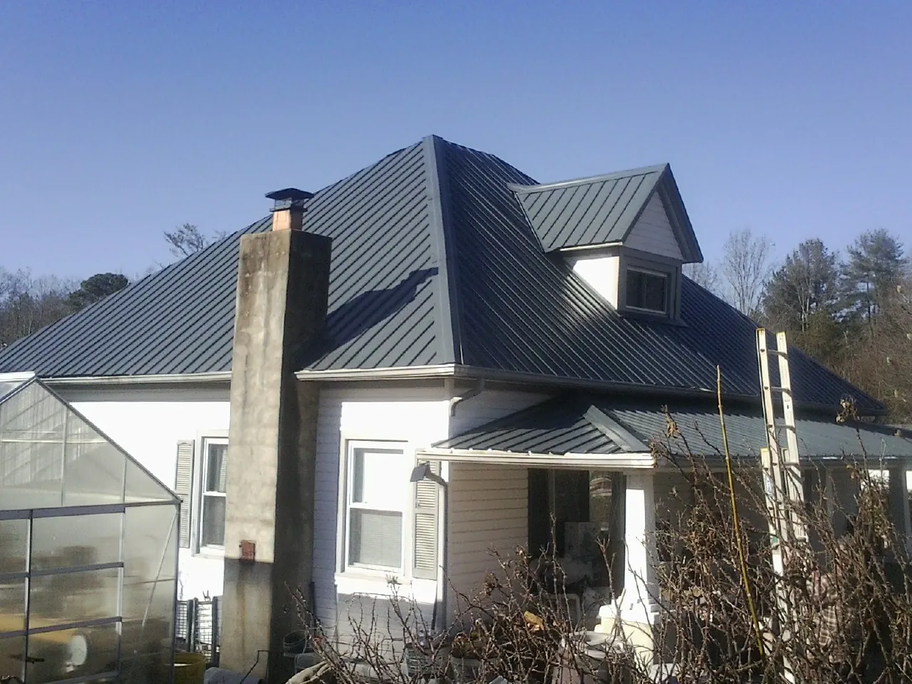 Dark blue standing seam metal roof on a white farmhouse with dormer — Slate & Tile Roof Repair by Roofing Brothers in Osakis