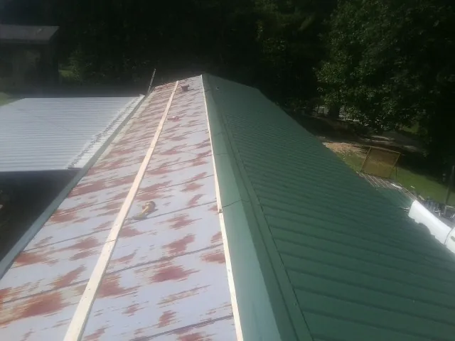 Old rusted panels beside newly installed green metal roofing — Wind Damage Roof Repair by Roofing Brothers in Osakis