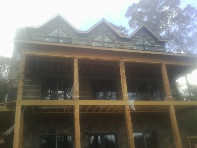 Dormers and porch framing on a large log home under construction — Roof Coating work by our crew in Osakis