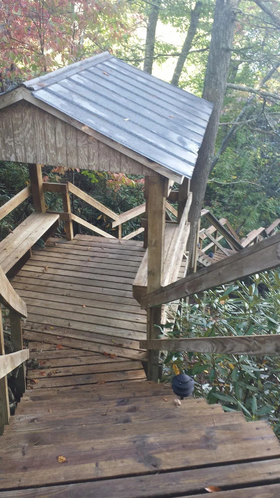 Metal roofed shelter over wooden steps on a wooded walkway — Skylight Repair & Installation work by our crew in Osakis