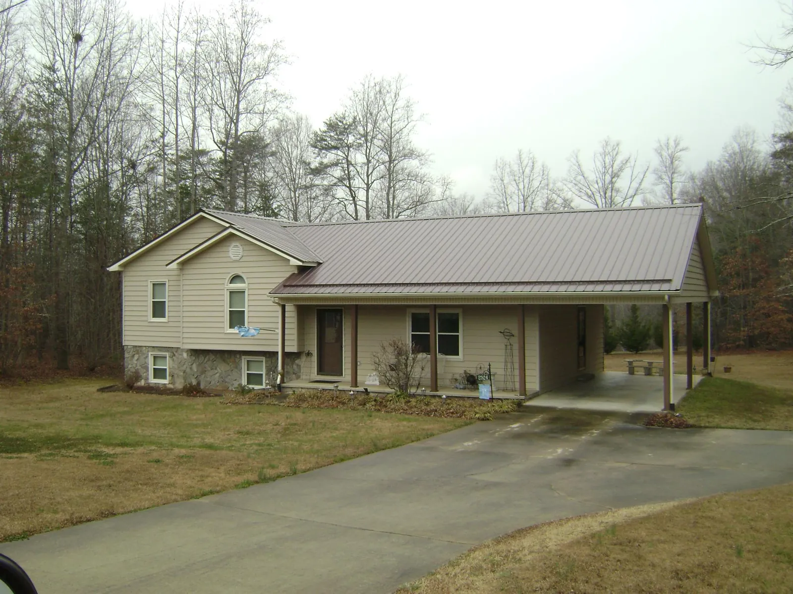 Brown metal roof on a tan split level home with an attached carport in Osakis