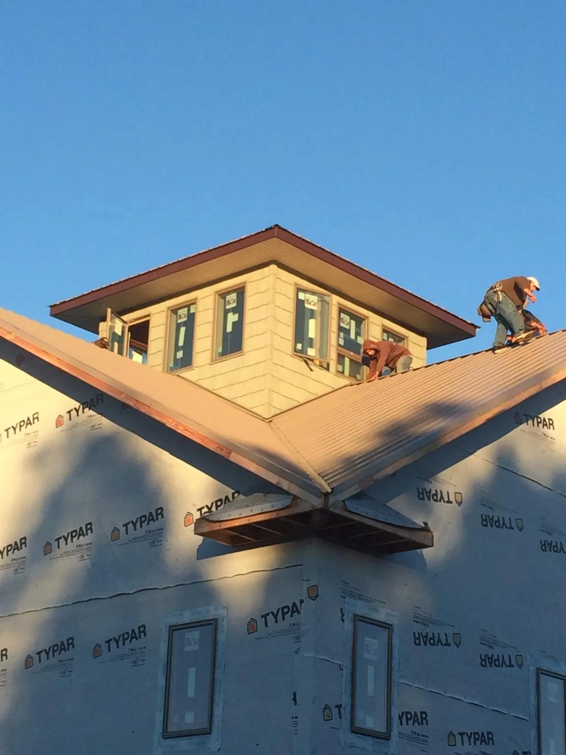 Roofers working around a rooftop cupola on a new metal roof at sunset — Roof Waterproofing in Osakis by Roofing Brothers